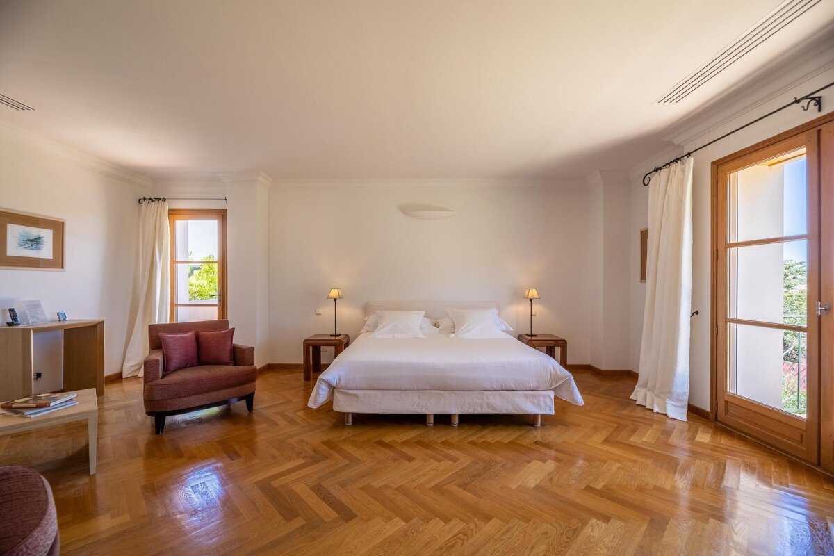A bedroom with a large bed and a chair