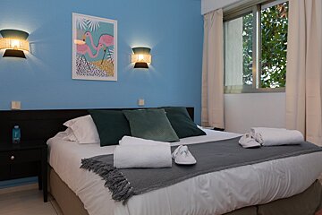 A bedroom with a bed and a picture of flamingos on the wall