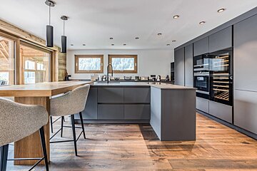 A kitchen with gray cabinets and a wine cooler