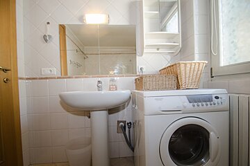 A bathroom with a washing machine and a sink