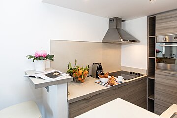 A kitchen with a vase of oranges on the counter