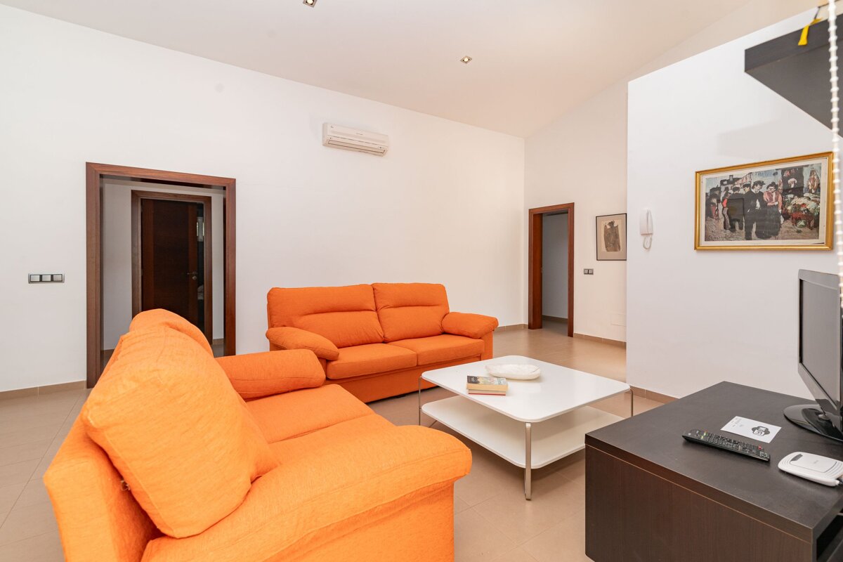 A living room with an orange couch and a white coffee table
