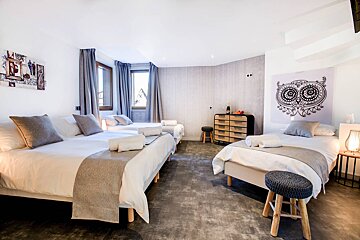 A bedroom with three beds and an owl on the wall