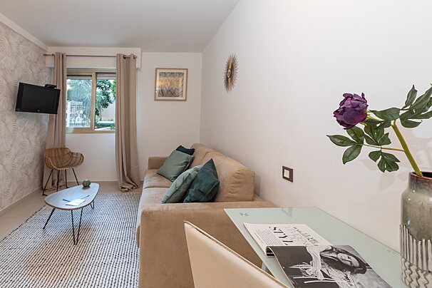 A living room with a couch a table and a vase of flowers
