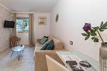 A living room with a couch a table and a vase of flowers