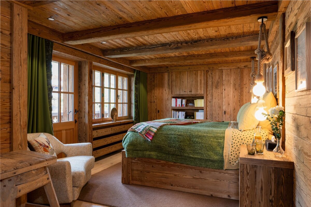 A wooden bedroom with a bed and a chair