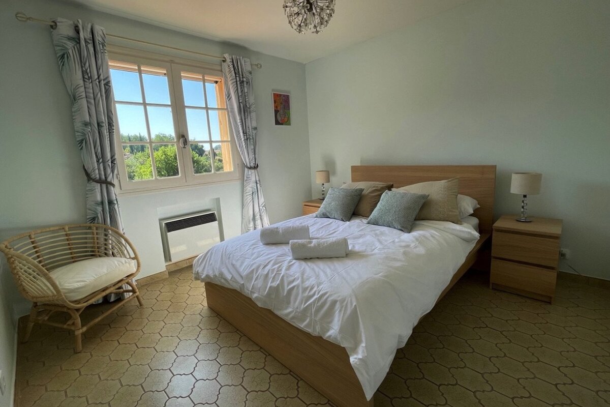 A bedroom with a wicker chair and a bed