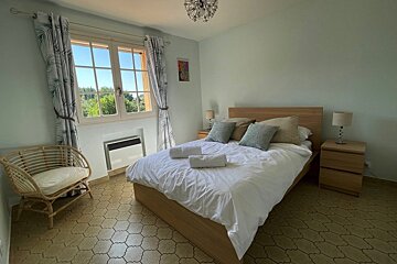 A bedroom with a wicker chair and a bed