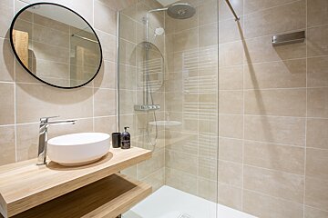 A bathroom with a walk in shower and a sink