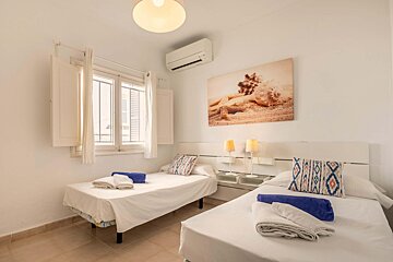 A bedroom with two beds and a painting on the wall