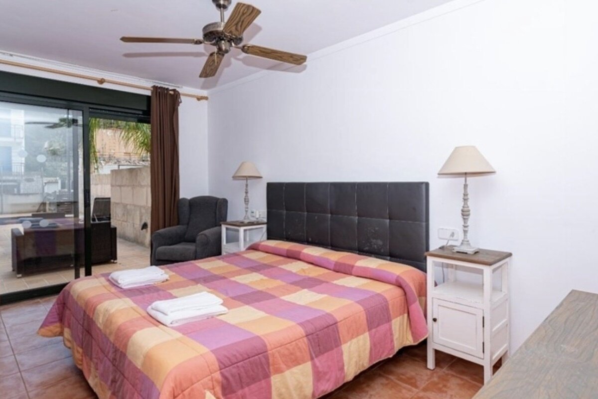 A bedroom with a large bed and a ceiling fan