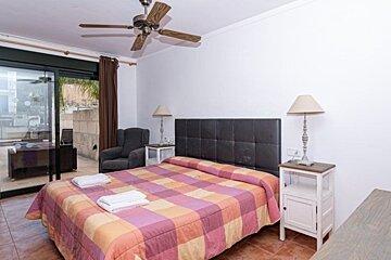 A bedroom with a large bed and a ceiling fan