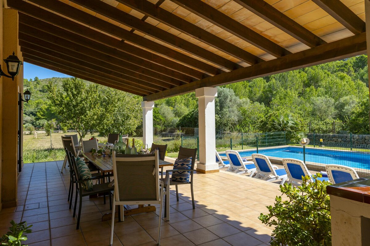 A patio with a table and chairs and a pool in the background