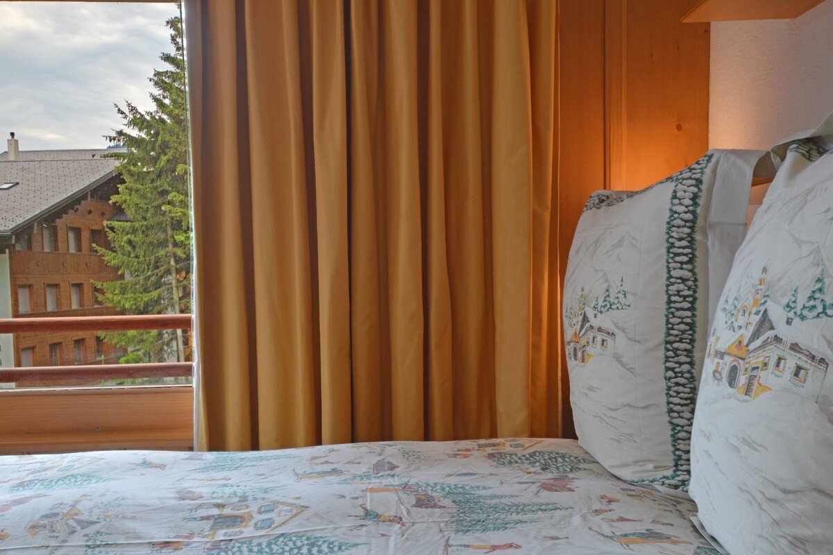 A bed with a pillow that has a snowy scene on it