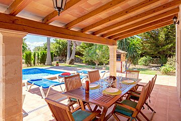A table and chairs on a patio with a pool in the background