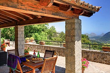 A patio with a table and chairs and a bottle of wine