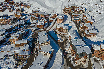 An aerial view of a snowy ski resort with buildings covered in snow