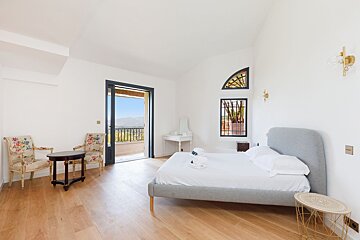 A bedroom with a large bed and two chairs