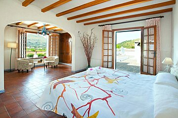 A bedroom with a king size bed and a balcony