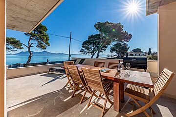 A table and chairs on a balcony overlooking the ocean