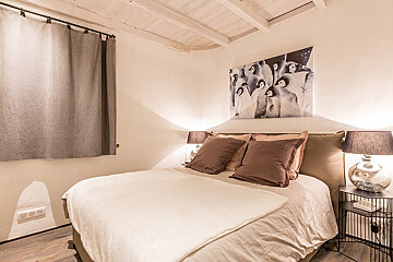 A bedroom with a painting of penguins on the wall above the bed