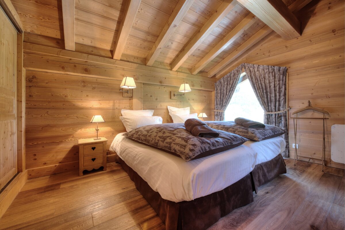 A bedroom with a wooden ceiling and two beds