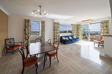 A living room with a blue couch and a table and chairs