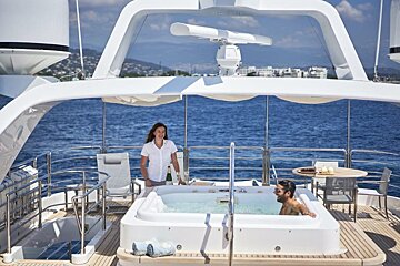 A man sits in a jacuzzi on the deck of a boat