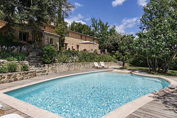 A large swimming pool in front of a stone house