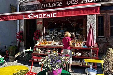 A woman stands in front of a store called l' epicerie