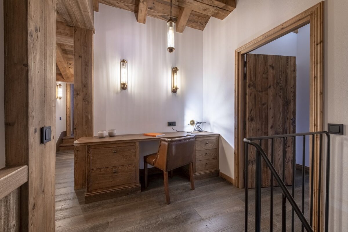 A wooden desk with a chair in a hallway