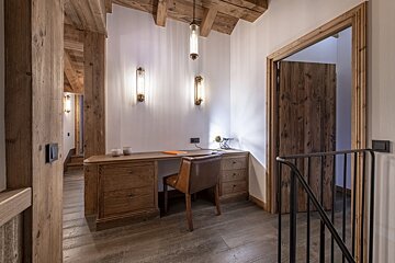 A wooden desk with a chair in a hallway