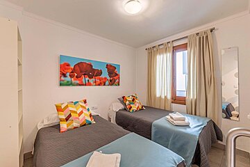 A bedroom with two beds and a painting of flowers on the wall