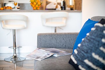 A couch with a magazine on it and a blue pillow