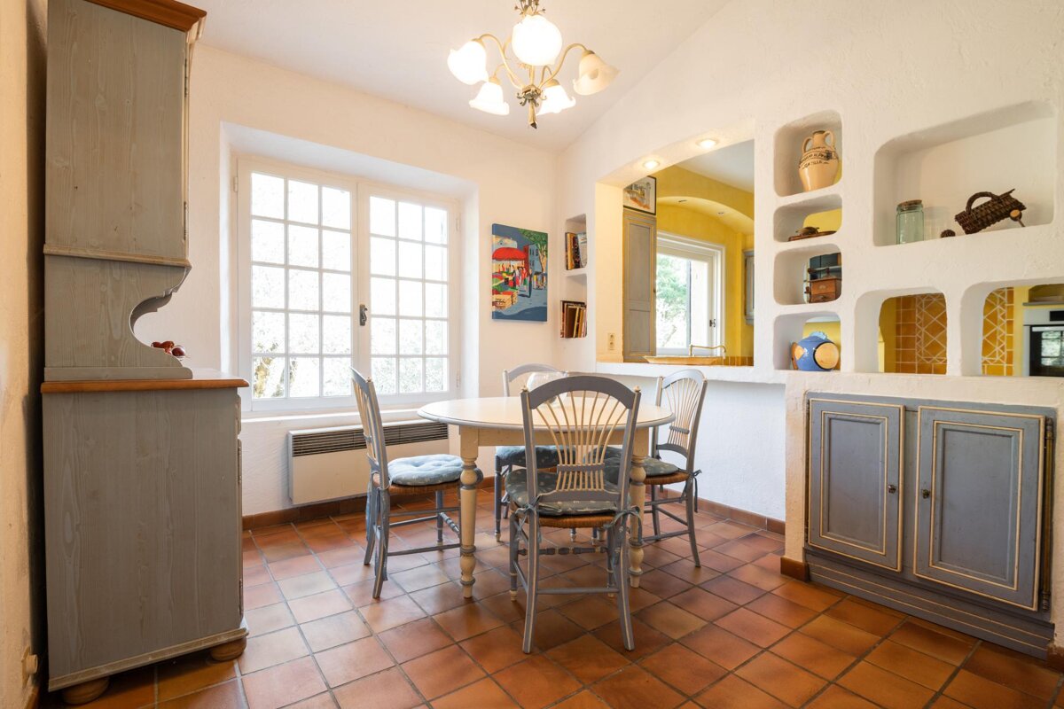 A dining room with a table and chairs and a painting on the wall