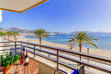 Two bottles of wine sit on a table on a balcony overlooking the ocean