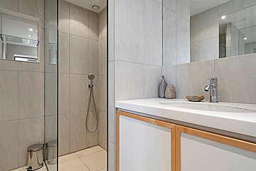 A bathroom with a walk in shower and a sink