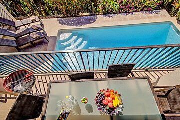 A table with a bowl of fruit on it in front of a pool
