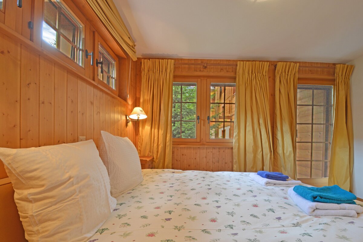 A bedroom with a bed and a window with yellow curtains