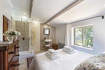 A bedroom with a walk in shower and a sink