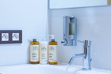 Three bottles of nuxe are on a bathroom sink