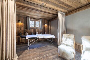 A wooden room with a massage table and chairs