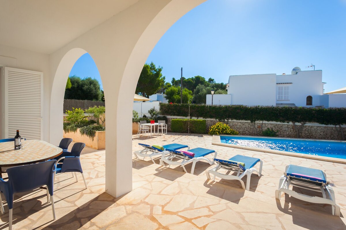 A patio with chairs and a table with a bottle of wine on it