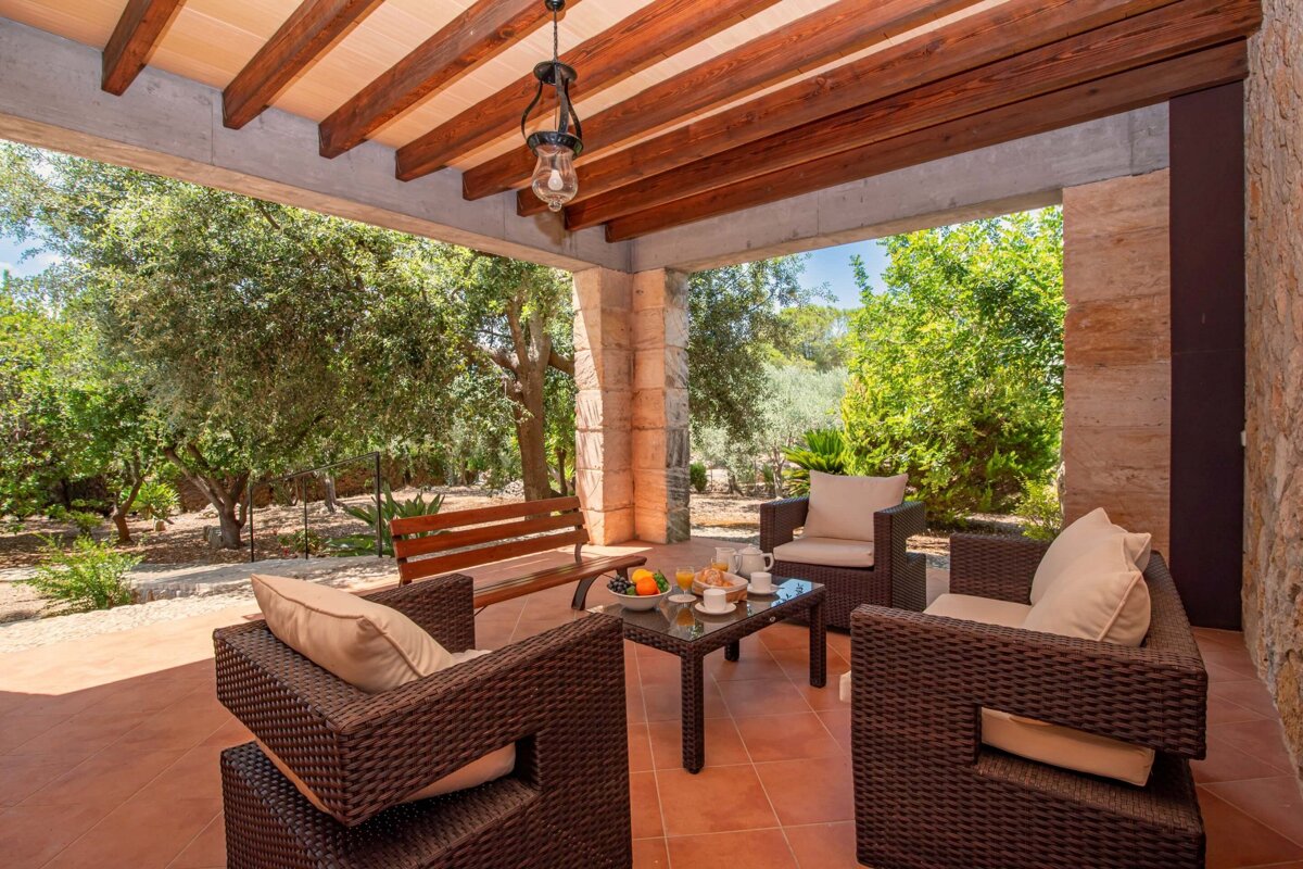 A patio with chairs and a table with a lantern hanging from the ceiling