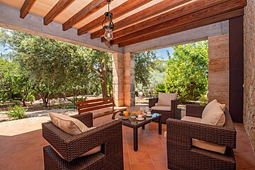 A patio with chairs and a table with a lantern hanging from the ceiling