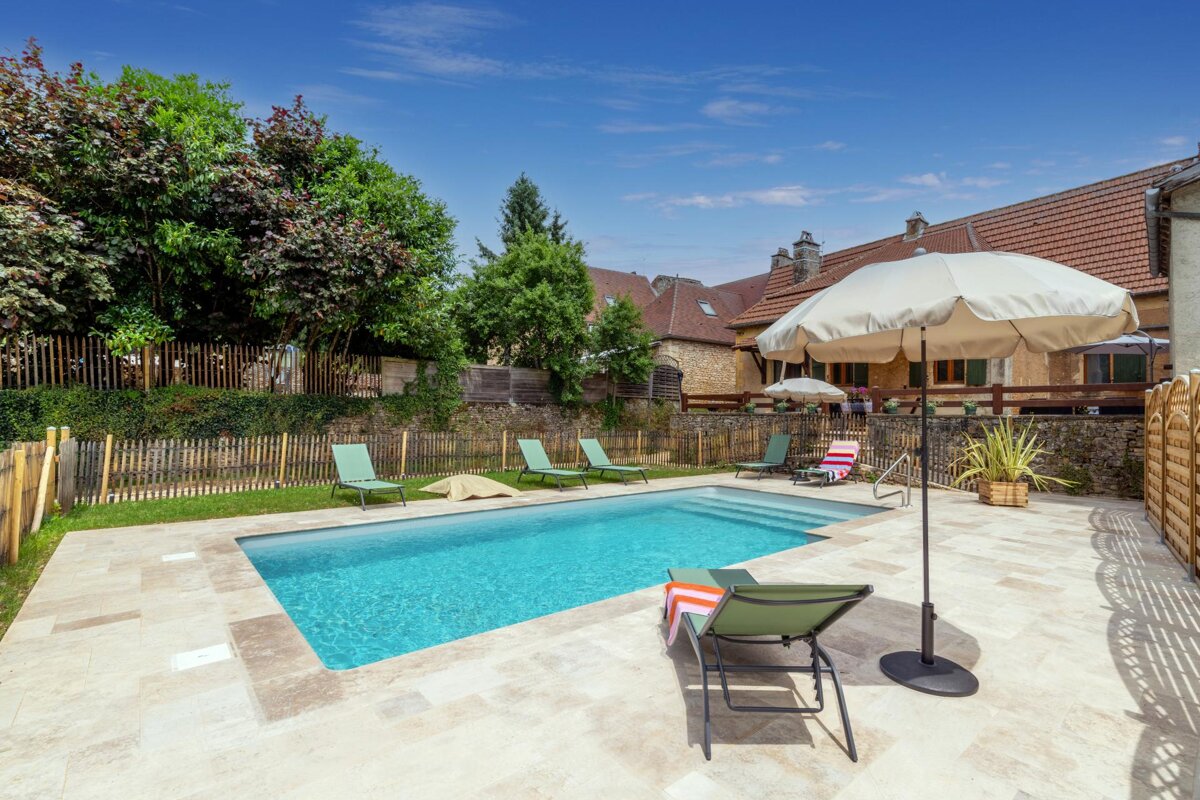 A swimming pool with chairs and umbrellas around it