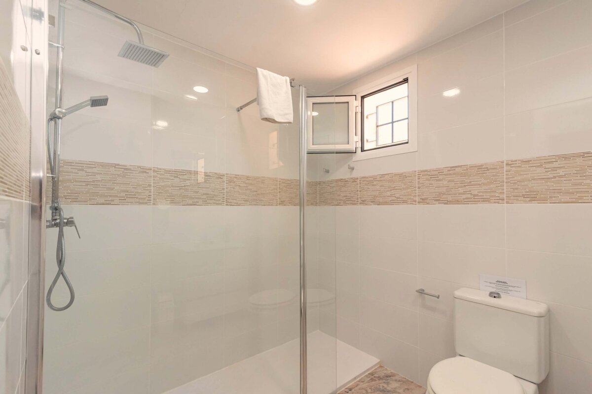 A bathroom with a toilet a shower and a window