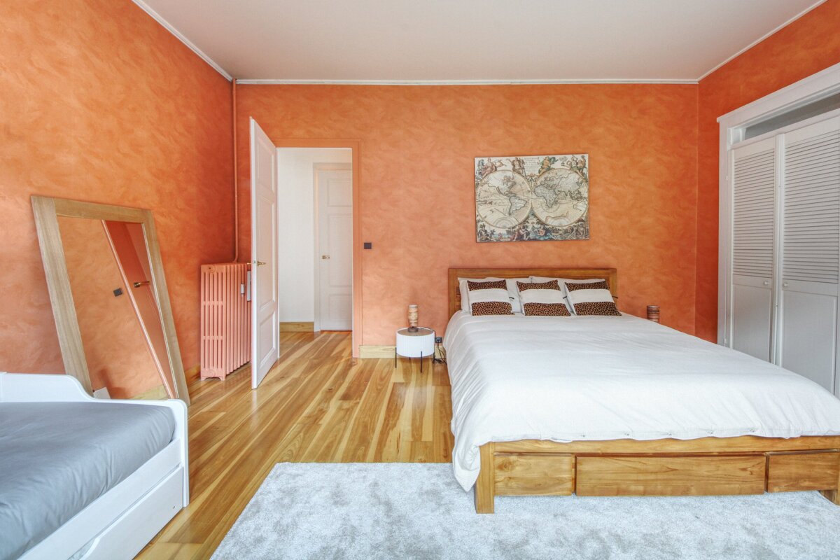 A bedroom with orange walls and a map on the wall above the bed