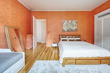 A bedroom with orange walls and a map on the wall above the bed