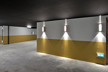 A hallway with yellow and white walls and lights on the walls